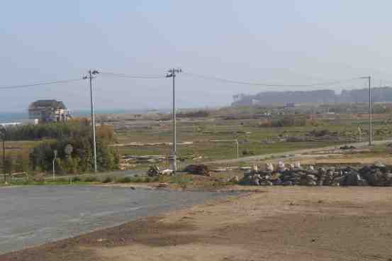 The barren tsunami ravaged plain of Namie with the reactors in the distance